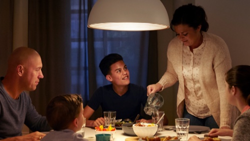 Family eating dinner at home under a well lit dinner table