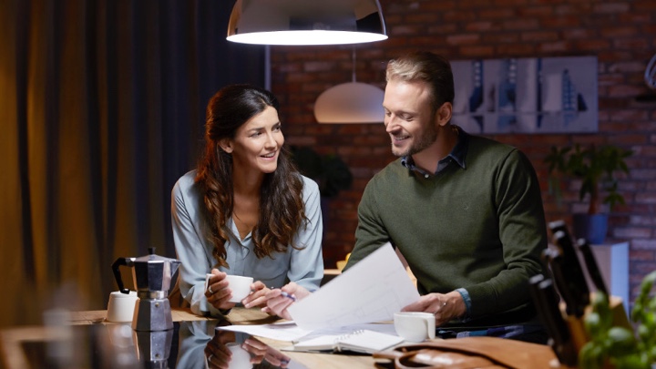 two people reading the newspaper under a dim luminaire