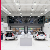 A modern car showroom with pendant lights illuminating several cars on display.